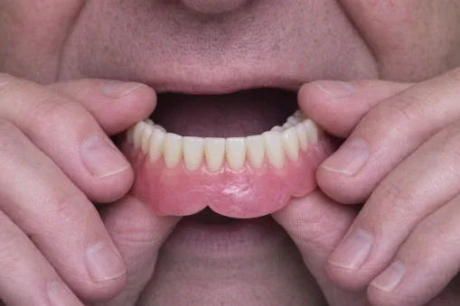 man putting dentures in mouth